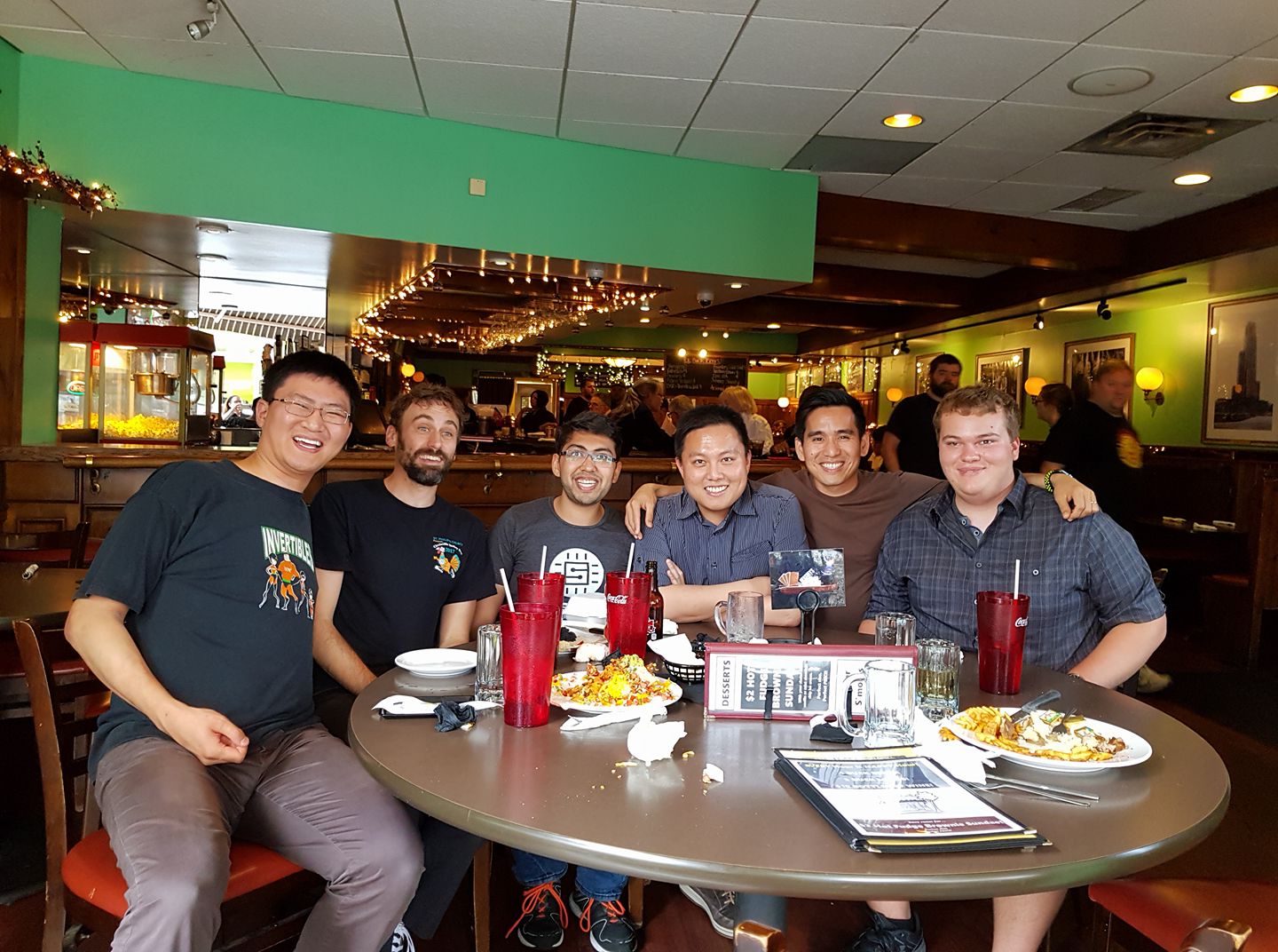 A picture of Cameron with his labmates, sitting around a table in a diner